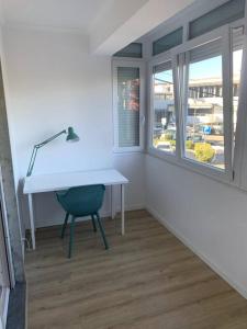 uma secretária branca com um candeeiro e uma cadeira num quarto em Carcavelos Beach Five Guests apartment em Oeiras