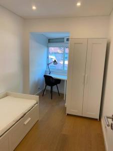 um quarto com uma cama, uma secretária e uma janela em Carcavelos Beach Five Guests apartment em Oeiras