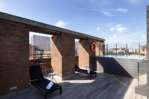 una terraza en la azotea con 2 sillas y una piscina en Catalonia Albeniz en Barcelona