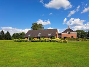 una casa grande con un césped verde delante de ella en B&B De Veluwe Hoeve, en Eerbeek