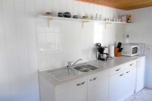 a white kitchen with a sink and a microwave at Ruegen_Fewo 67_1 in Thesenvitz