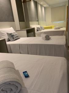 クリチバにあるHotel Dois Irmãosの白いシーツと青いアイテムが備わるベッド3台が備わる部屋