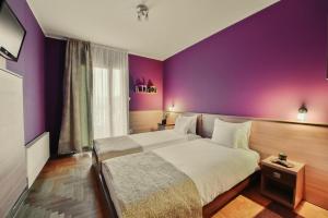 Vrnjačka Banja的住宿－Apartmani Lenka，酒店客房设有两张床和紫色的墙壁。