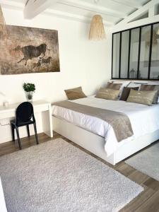 a white bedroom with a large bed and a desk at Bastide Magdaleyna Mougins in Mougins