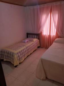 2 camas en una habitación con cortinas rosas en Los Olivos en Puerto Iguazú