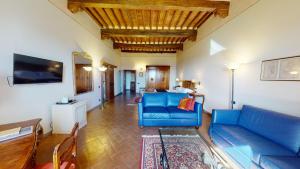 a living room with a blue couch and a tv at Hotel Palazzo Squarcialupi in Castellina in Chianti