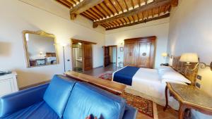 a bedroom with a bed and a couch and a mirror at Hotel Palazzo Squarcialupi in Castellina in Chianti