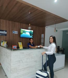 a woman standing at a counter with her luggage at Hotel Prado 53 in Barranquilla