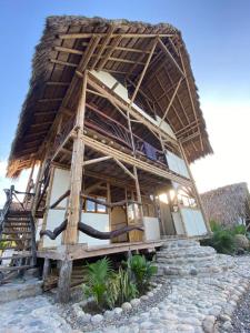 a house with a thatched roof on top of a stone floor at Playa Cataro Boutique Ecolodge A in Palomino