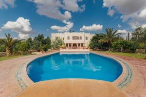 a large swimming pool in front of a white house at Riad le Ksar de Fes in Aïn Cheggag