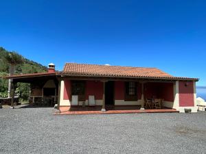 Casa roja y blanca con mesa y sillas en Casa Los Calderos, en Mazo