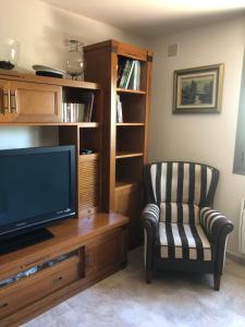 ein Wohnzimmer mit einem TV und einem Stuhl in der Unterkunft Casa Candelaria in Arguedas