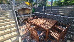 un patio con mesa de madera y horno de ladrillo en Apartments Blazevic, heated pool&jacuzzi, en Dramalj