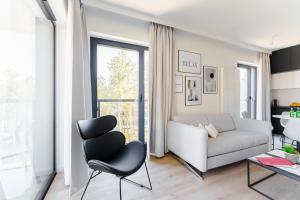 a living room with a couch and a chair at Apartament Sunrise Shellter - Rogowo in Dźwirzyno