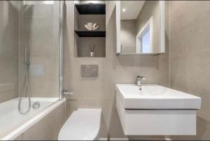 a bathroom with a sink and a toilet and a tub at 1 bed Apartment with parking & GYM in Slough