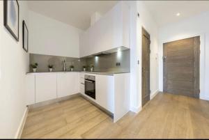 a kitchen with white cabinets and a wooden floor at 1 bed Apartment with parking & GYM in Slough