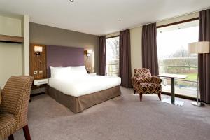 a hotel room with a bed and a desk and chair at Cedar Court Hotel Harrogate in Harrogate