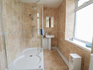 a bathroom with a shower and a tub and a sink at Rowan Cottage in Builth Wells