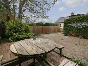 a wooden picnic table in a backyard with a fence at Rowan Cottage in Builth Wells