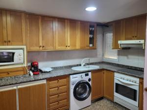 a kitchen with a washing machine and a microwave at carrer de la pau port de sagunto in Valencia