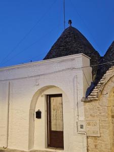 un bâtiment blanc avec une porte et un toit noir dans l'établissement TRULLO AURORA BOREALE, à Alberobello