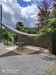 una mesa y sillas en un patio con una valla en Cottage les hôtes Pyrénées, en Capvern