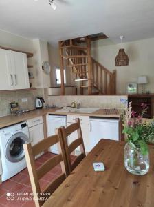 cocina con mesa y lavadora en Cottage les hôtes Pyrénées, en Capvern