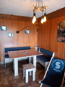 uma sala de jantar com uma mesa e bancos azuis em Appartement chalet en plein centre des Saisies em Hauteluce
