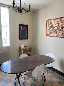 a dining room with a table and white chairs at Appartement charmant centre ville in Narbonne