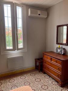 a bedroom with a dresser and a mirror and window at Appartement charmant centre ville in Narbonne