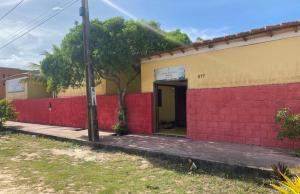 a red and yellow building with a red wall at Pousada Sem Stress Porto Itália in Nova Viçosa