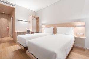 uma grande cama branca num quarto de hotel em Moov Hotel Lisboa Oriente em Lisboa