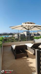 een patio met een parasol, 2 stoelen en een tafel bij Tolip Resort Paradise New- Alamein in Marsa Matruh