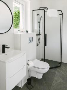 een witte badkamer met een toilet en een douche bij Domek Moszna in Moszna