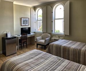 um quarto de hotel com duas camas, uma secretária e uma cadeira em Lunenburg Arms Hotel em Lunenburg
