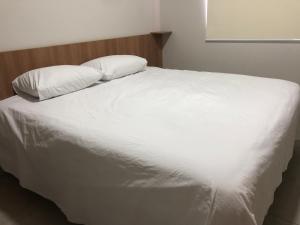 un grande letto bianco con due cuscini sopra di Vêneto Flat Residence (AP-02) a Primavera do Leste