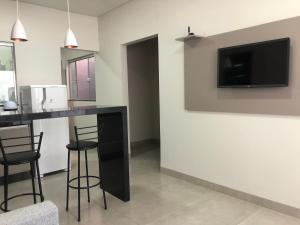un soggiorno con bar e TV a parete di Vêneto Flat Residence (AP-02) a Primavera do Leste