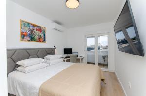 een witte slaapkamer met een groot bed en een bureau bij Modern living apartment Airy in Split