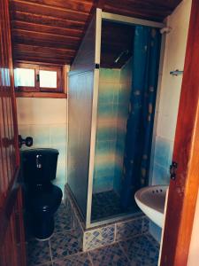 a bathroom with a shower and a toilet and a sink at Hostería Cacique Wasi in Puyo