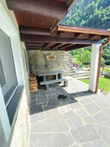 a patio with a bench under a stone wall at Rustico Chiara in Sonogno