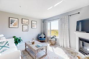 een woonkamer met een witte bank en een open haard bij Surf's Up in Westport