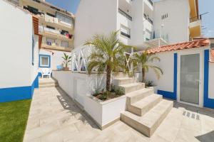 a facade of a building with stairs and palm trees at Pátio C'un Casinhas in Nazaré