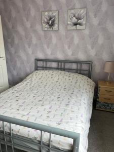 a bed in a bedroom with three pictures on the wall at Treetops - Sleeps 8 entire house private parking close to town centre and stadium in Wigan