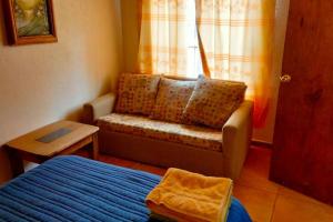 a bedroom with a bed and a couch and a window at Casa Nantly Patzcuaro in Pátzcuaro