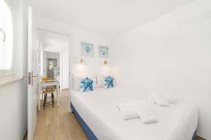 a white bedroom with a white bed and a desk at Pátio C'un Casinhas in Nazaré