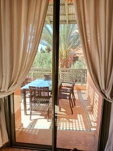 une porte coulissante en verre menant à une terrasse avec une table et des chaises. dans l'établissement palmeraie village 2, à Marrakech