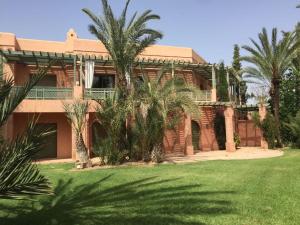 une grande maison en briques avec des palmiers devant elle dans l'établissement palmeraie village 2, à Marrakech