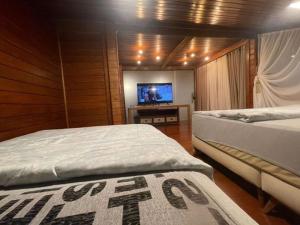een slaapkamer met 2 bedden en een flatscreen-tv bij Casa do Lago Pinhal in Rio dos Cedros