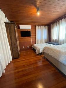 1 dormitorio con 2 camas y suelo de madera en Casa do Lago Pinhal, en Rio dos Cedros