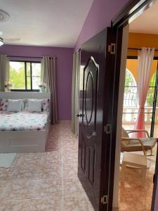 een slaapkamer met paarse muren, een bed en een raam bij Casa Francesca in Boca Chica